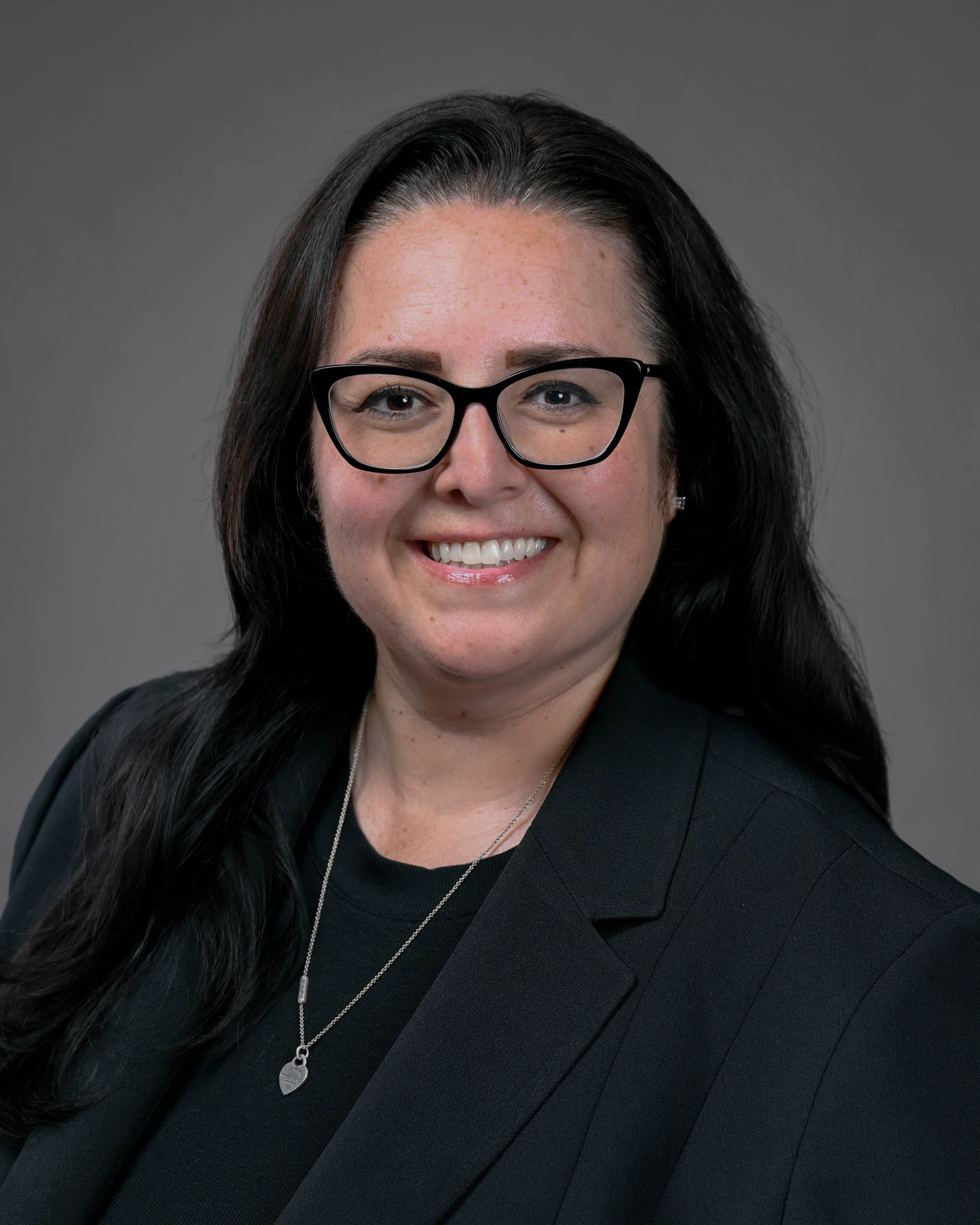 Smiling woman with long dark hair in a dark suit